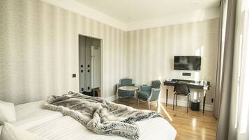 A hotel room with a bed, a desk, two chairs, a television, and a door.