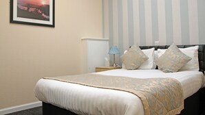 A neatly made bed with a patterned bedspread, a bedside lamp, and a framed picture on the wall. - The Elgin Kintore Arms, Inverurie (Inverurie)