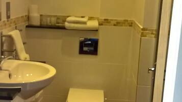 A bathroom with a sink, toilet, and a towel dispenser.