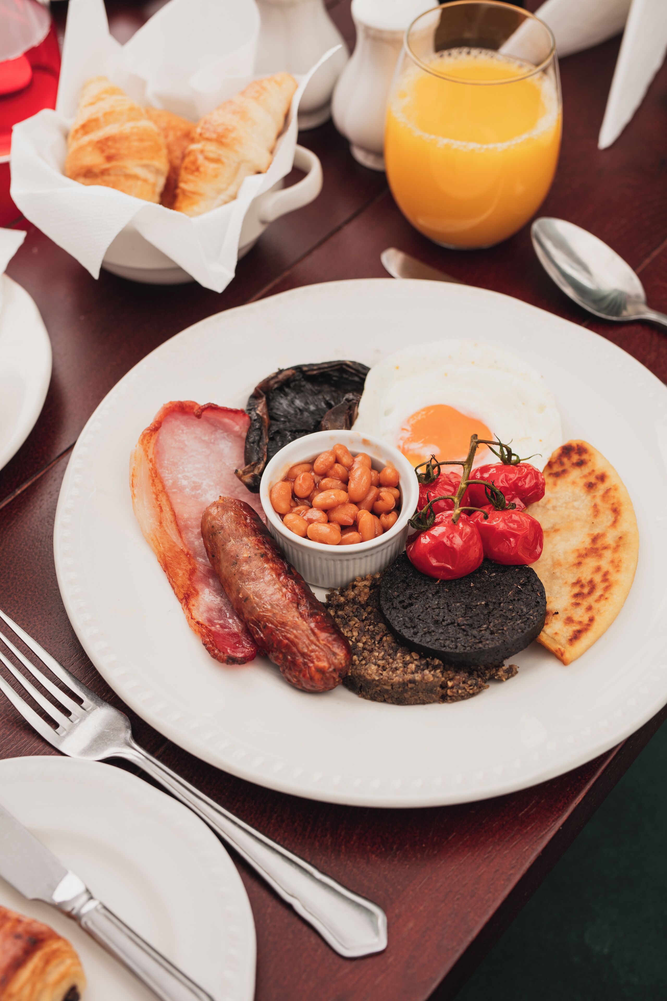 A breakfast plate with eggs, sausages, beans, and tomatoes.