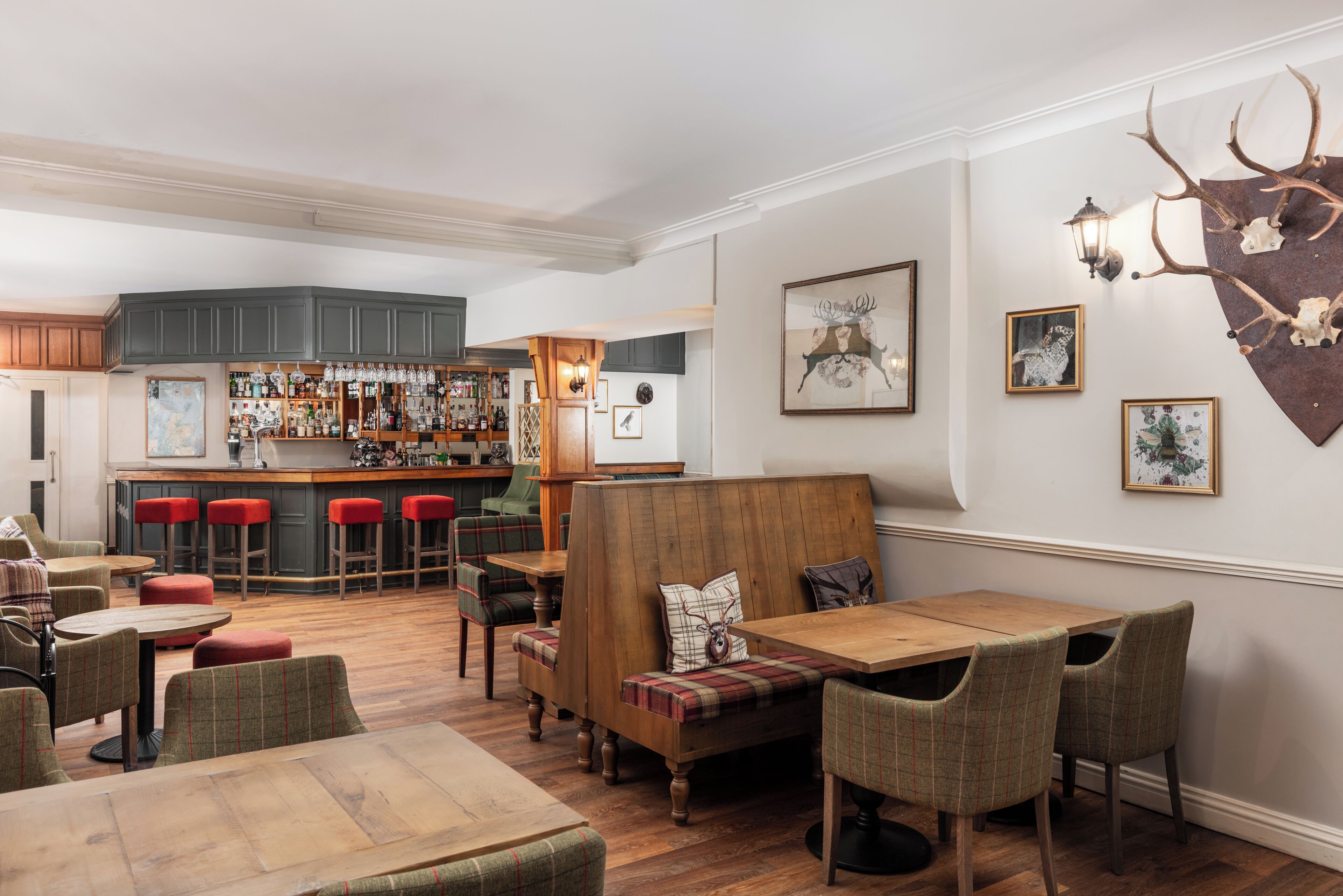 A cozy bar area with wooden furniture and a bar stocked with bottles.