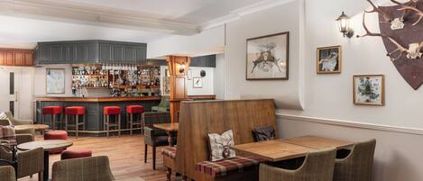 A cozy bar area with wooden furniture and a bar stocked with bottles.