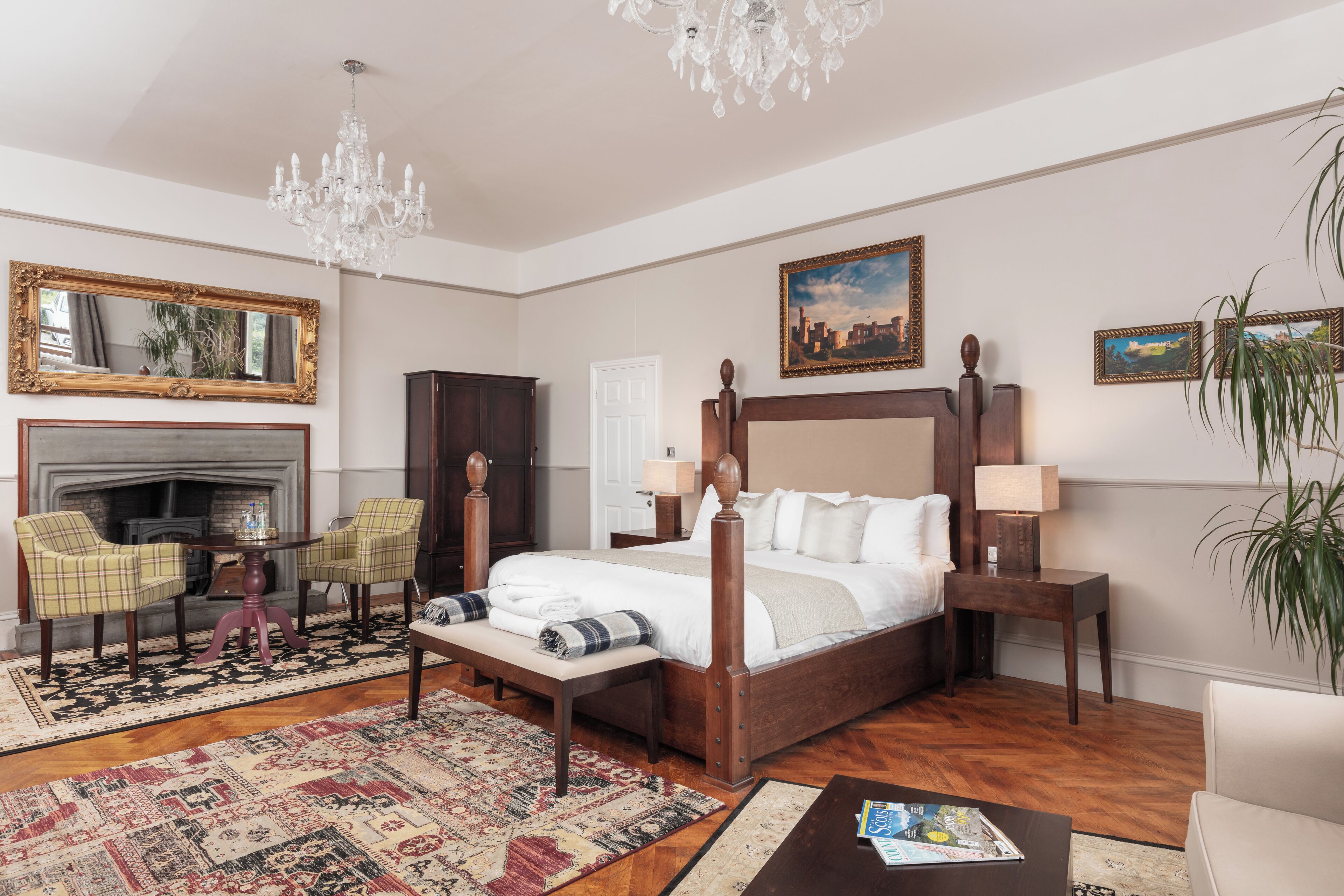 A spacious bedroom with a large bed, a chandelier, a fireplace, and a view of the city.