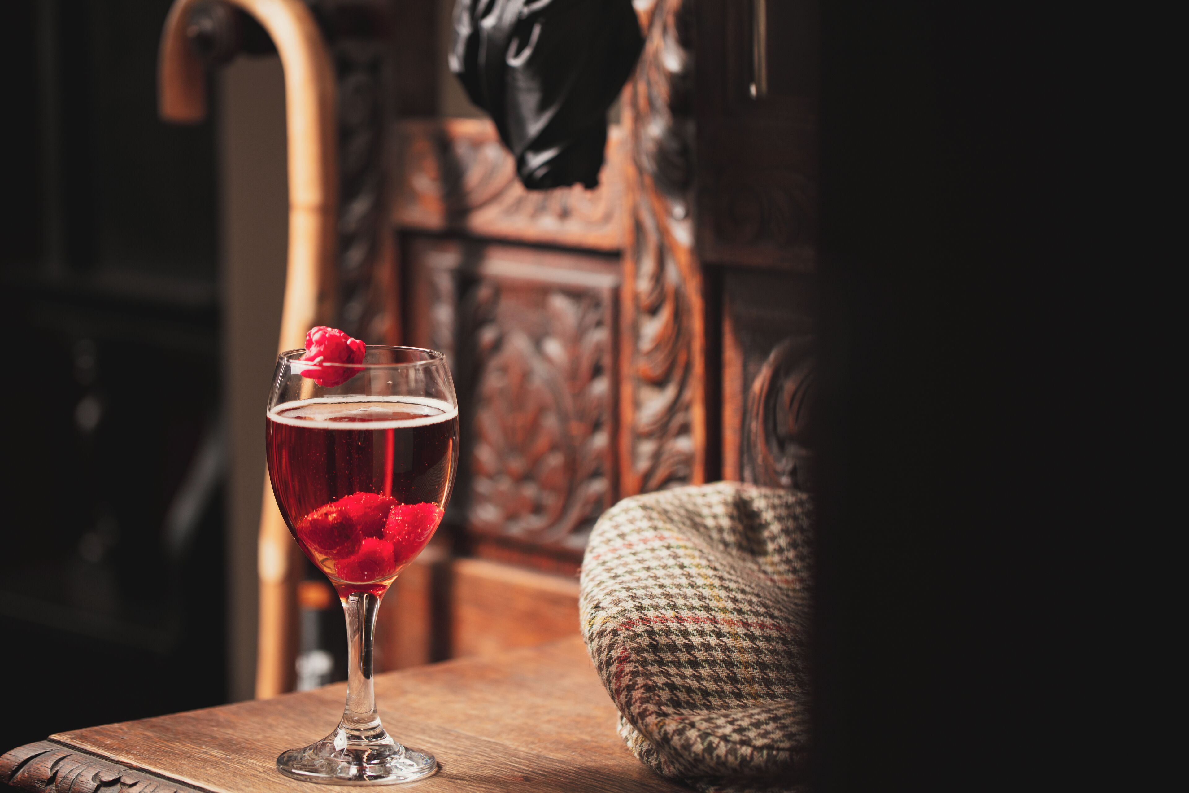 Un vaso de bebida roja con una fruta roja sobre una mesa de madera.