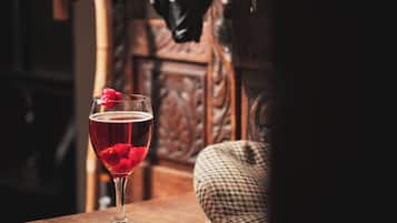 Un vaso de bebida roja con una fruta roja sobre una mesa de madera.