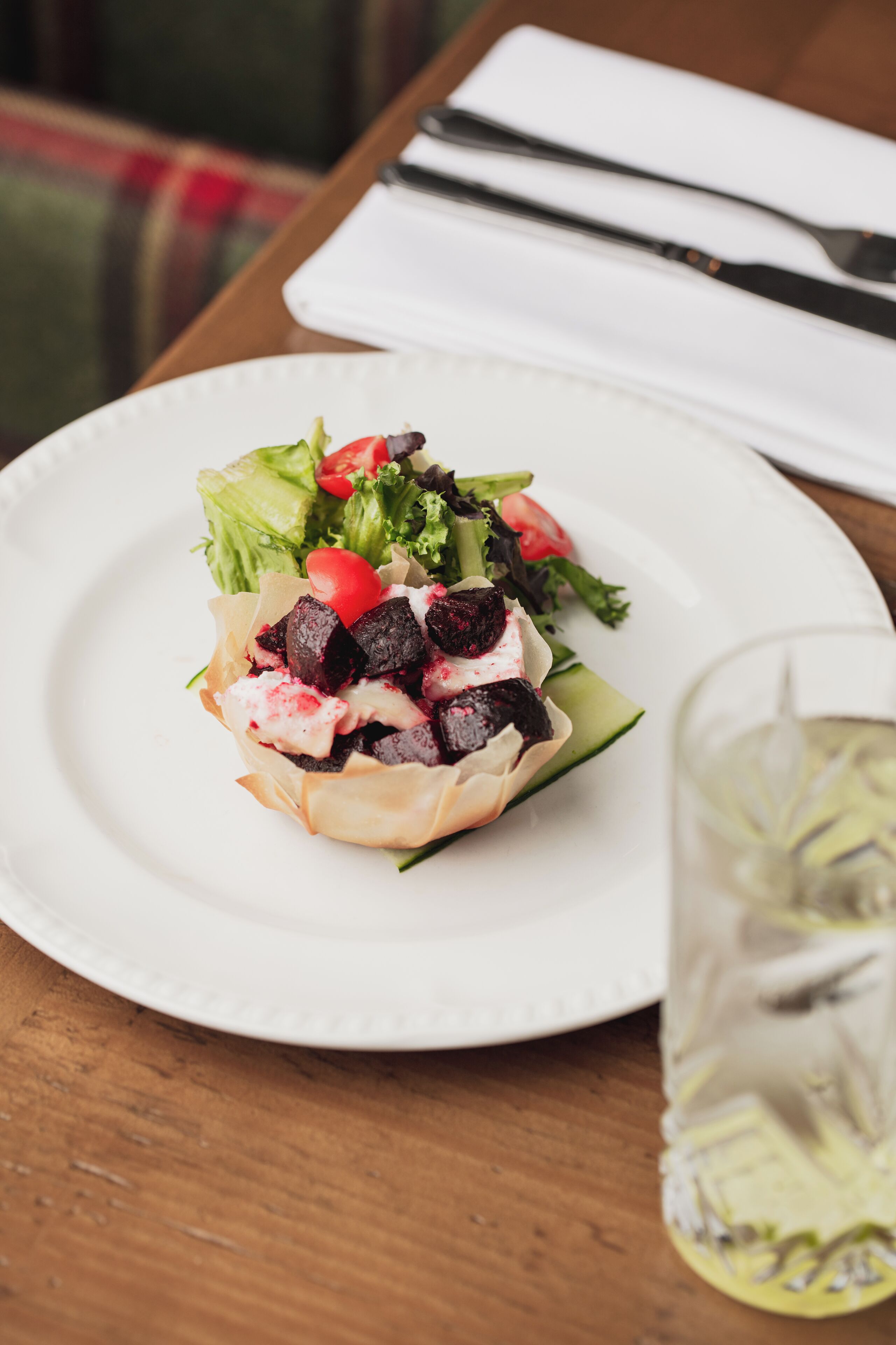 Um prato branco com uma salada sobre uma mesa de madeira.