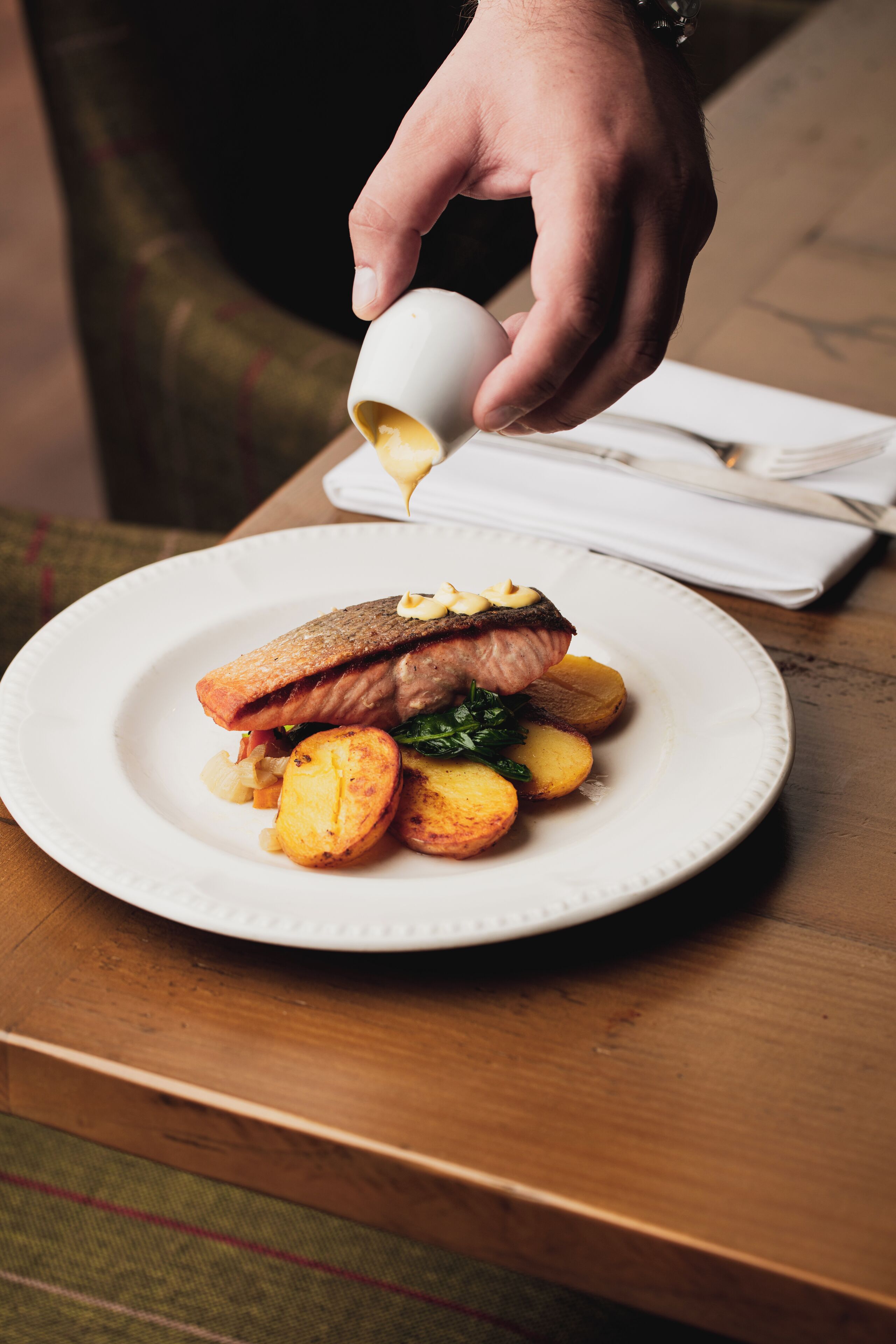 Une assiette contenant un morceau de saumon, des pommes de terre rôties et une garniture.