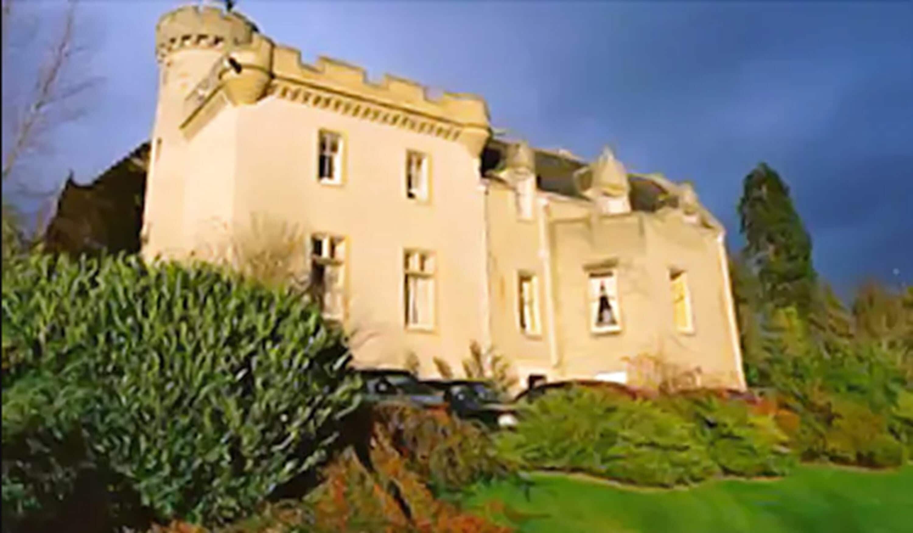 A large, historic building with multiple windows and a prominent tower, surrounded by lush greenery.