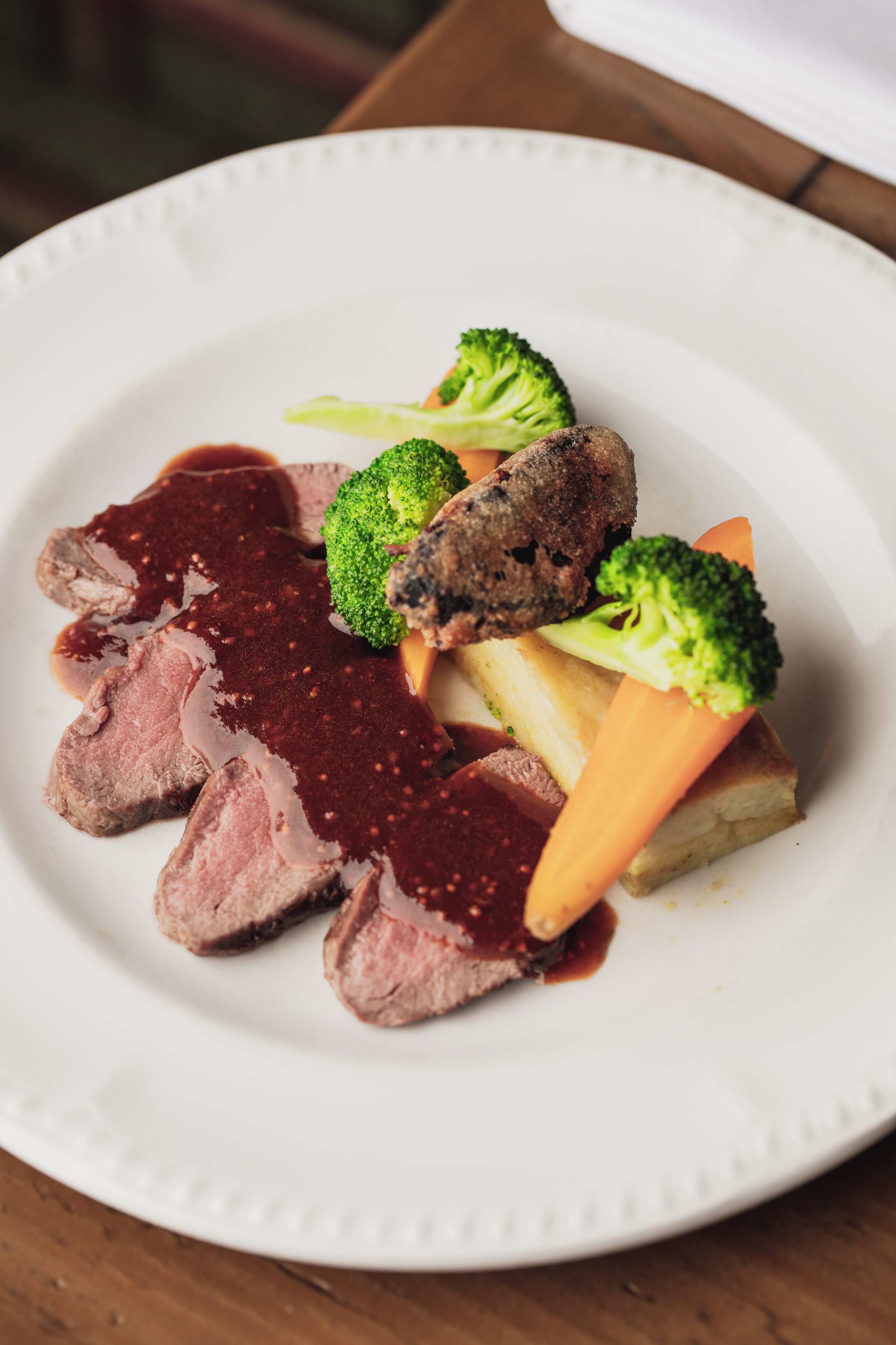 Un plato de comida con rebanadas de carne, brócoli y zanahorias.