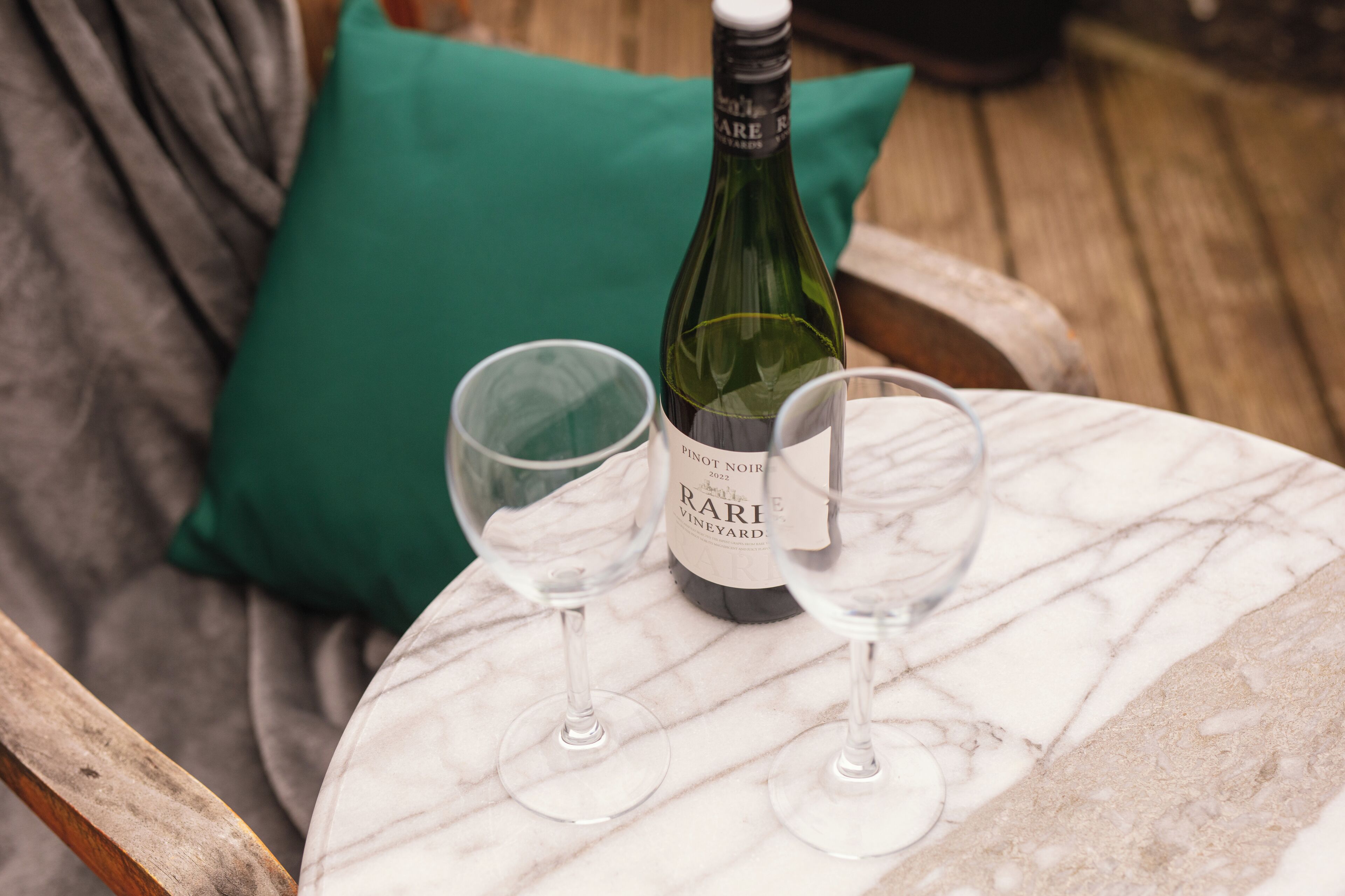 Una botella de vino y dos copas sobre una mesa de mármol.