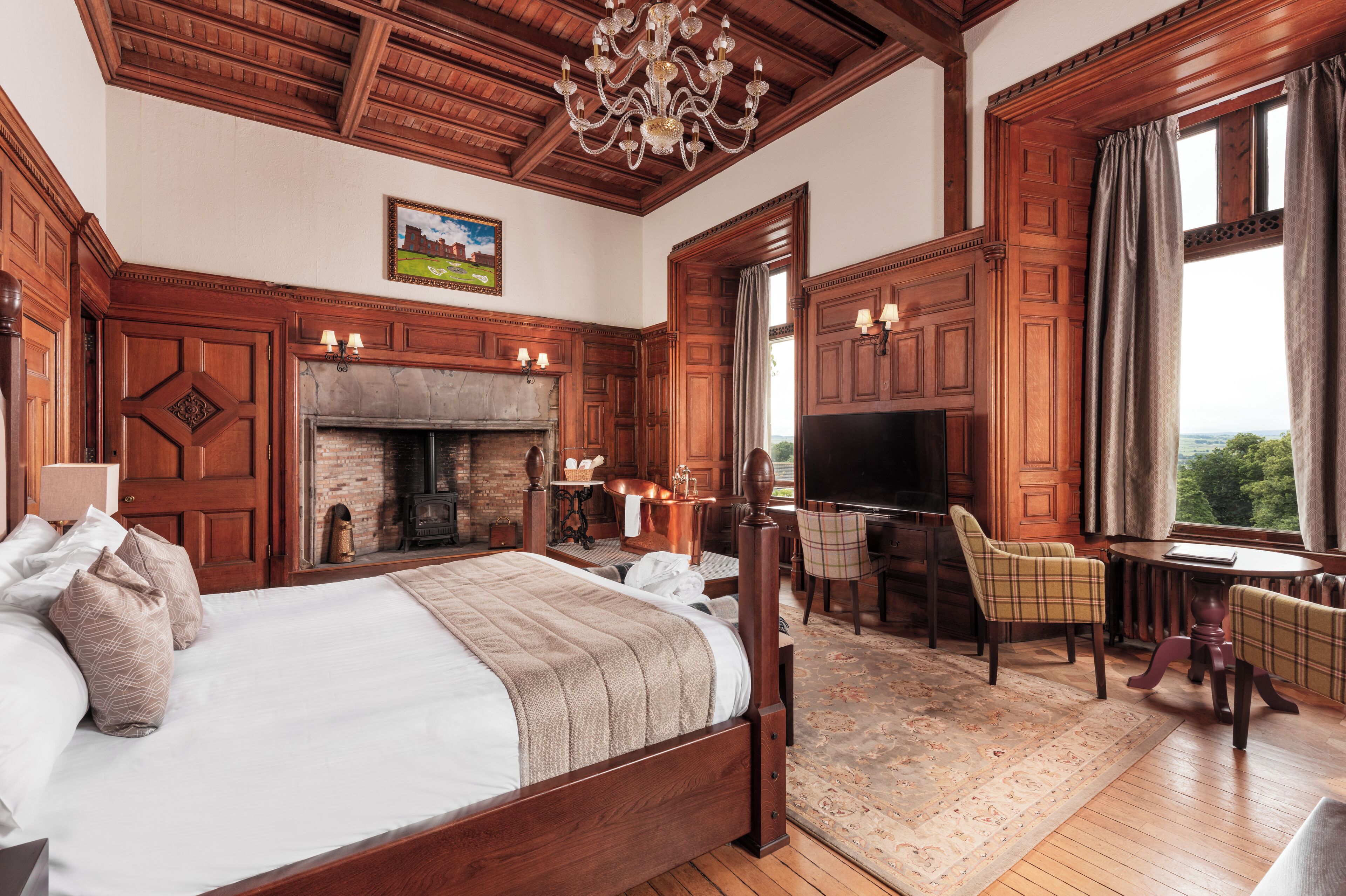 A spacious bedroom with a large bed, a fireplace, a television, and a view of the outdoors.