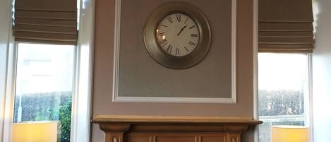 A room with a fireplace, a clock, and a chandelier.