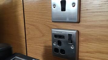 A wall-mounted USB charger with a USB port and a 2.1A-5V label, a power outlet, and a control panel with a display and buttons.