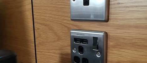 A wall-mounted USB charger with a USB port and a 2.1A-5V label, a power outlet, and a control panel with a display and buttons.