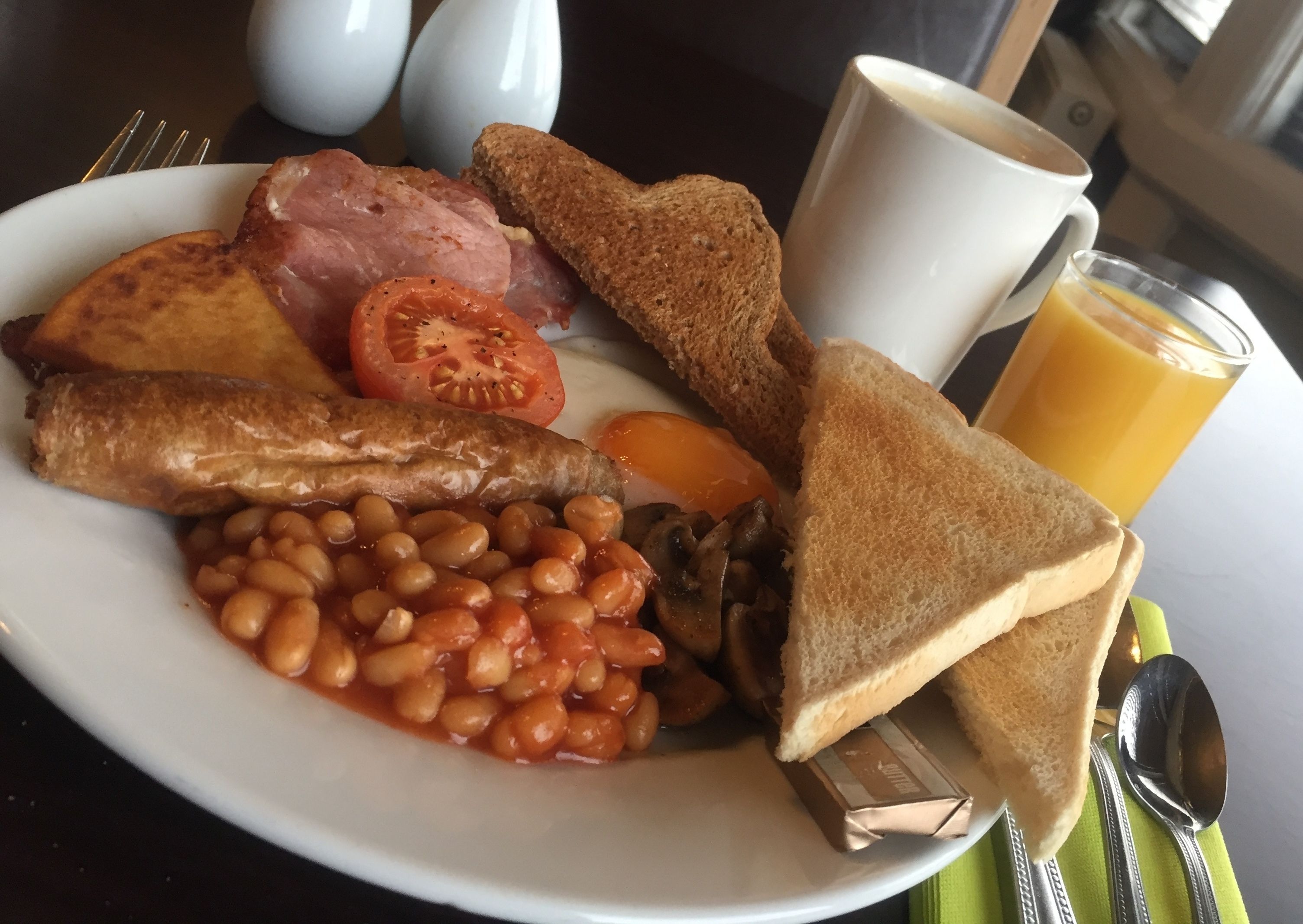 A plate with toast, beans, tomatoes, mushrooms, and ham.