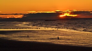 Una playa al atardecer con cielo despejado y mar tranquilo.
