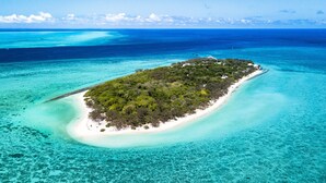 An aerial view of a small island with clear turquoise waters and a white sandy beach.