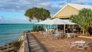 A seaside patio with outdoor seating and a view of the ocean.