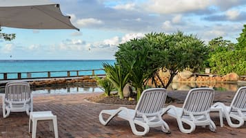 Relax in a serene outdoor seating area with ocean views, lounge chairs, and a small table.