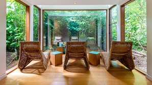 A room with large glass windows, wicker chairs, and a wooden floor.