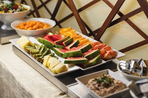 Buffet com diversas frutas e uma tigela de castanhas.