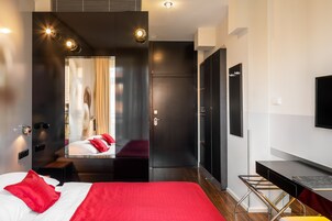 Quarto de hotel moderno com uma cama grande, uma escrivaninha e um espelho.
