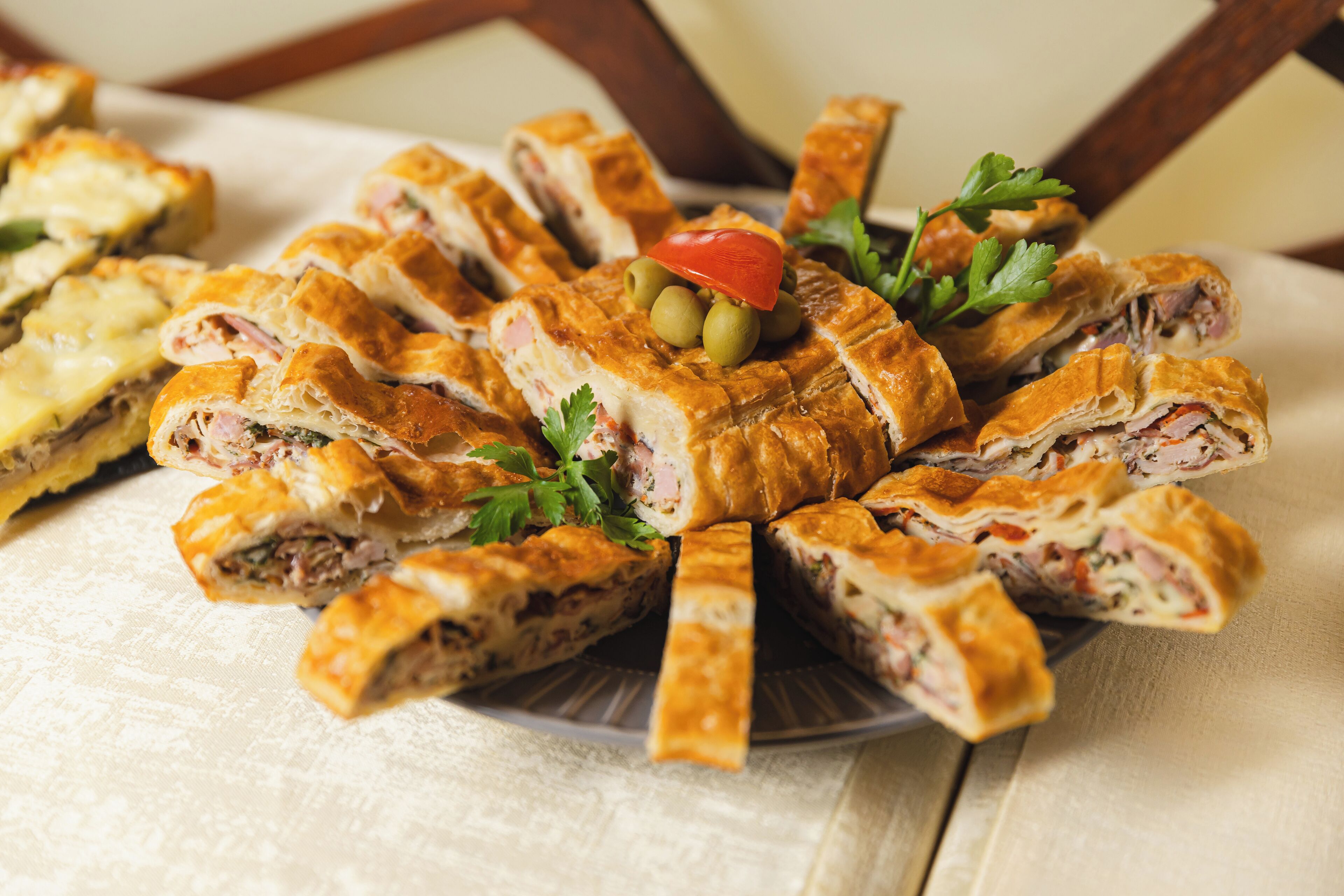 A plate of sliced pastries with olives and parsley garnish.