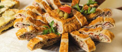 A plate of sliced pastries with olives and parsley garnish.