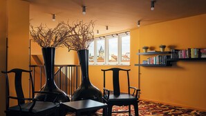 A room with a large window, a bookshelf, two chairs, and two vases.