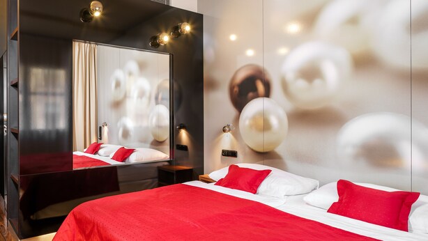 A modern hotel room with a large bed, a mirror, and a wall with spherical decorations.