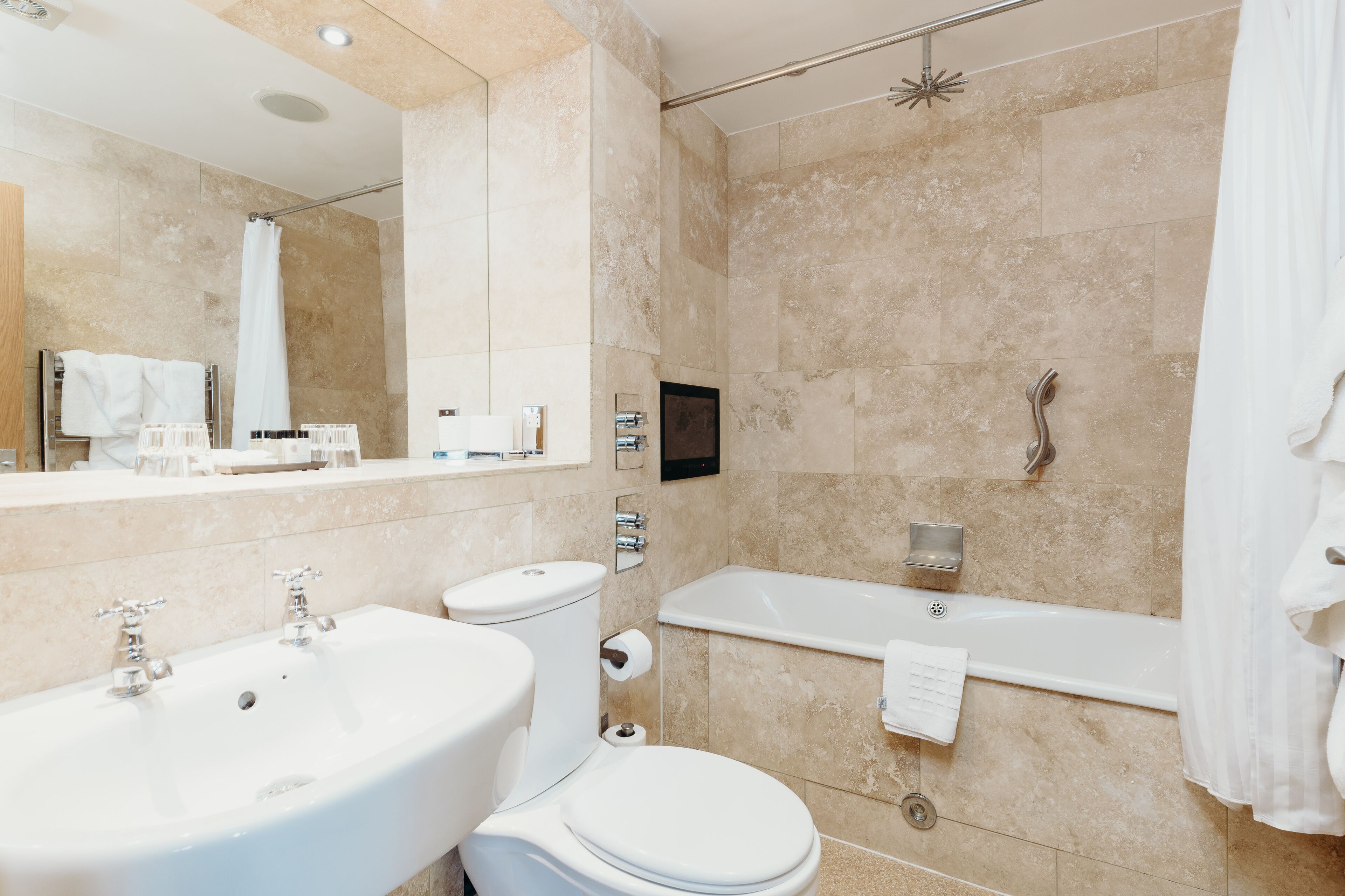 A modern bathroom with a sink, toilet, and bathtub.