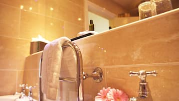 Un baño con una toalla colgada en un perchero, un lavabo y un espejo sobre él.