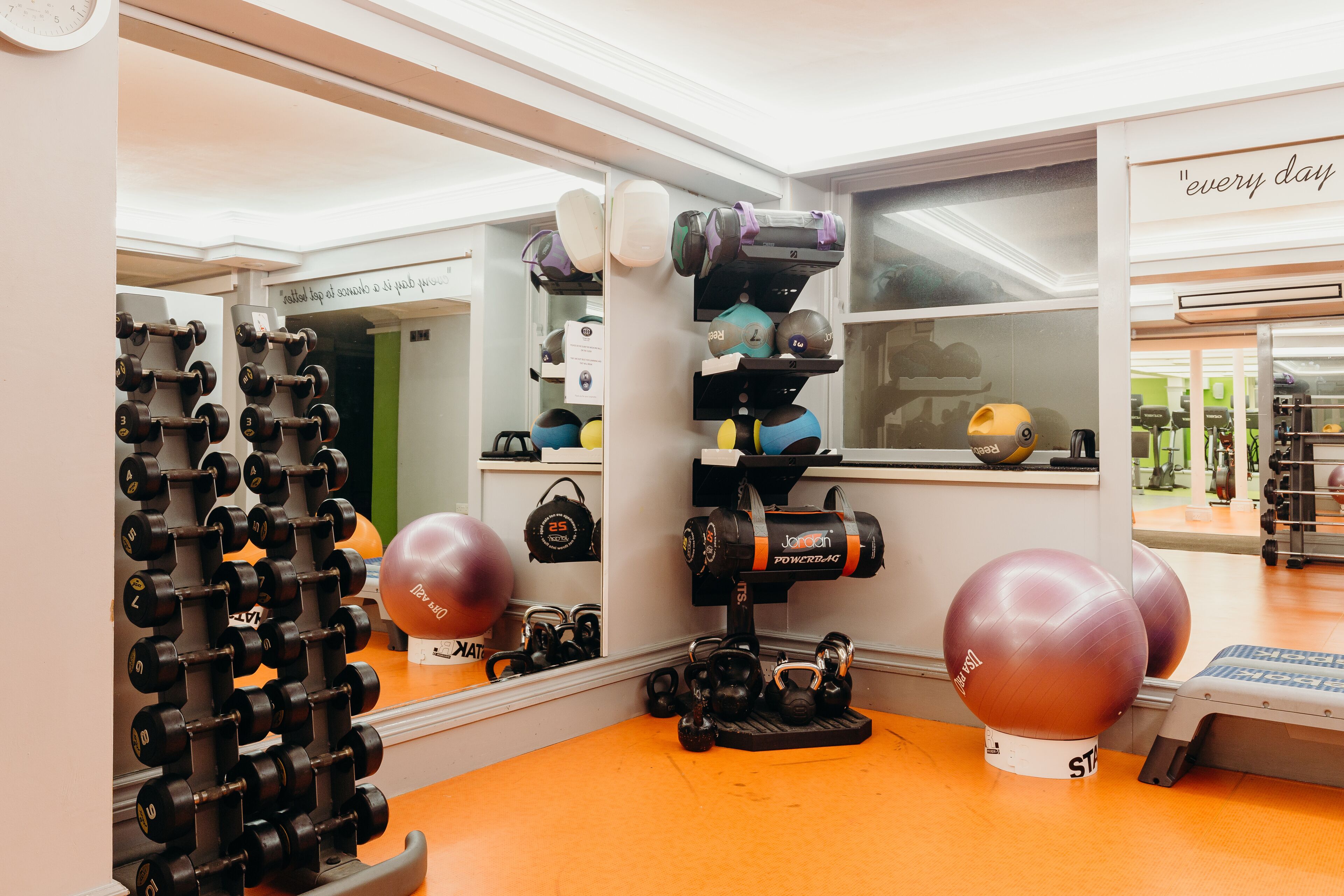 A gym with exercise equipment, a mirror, and a motivational quote on the wall.