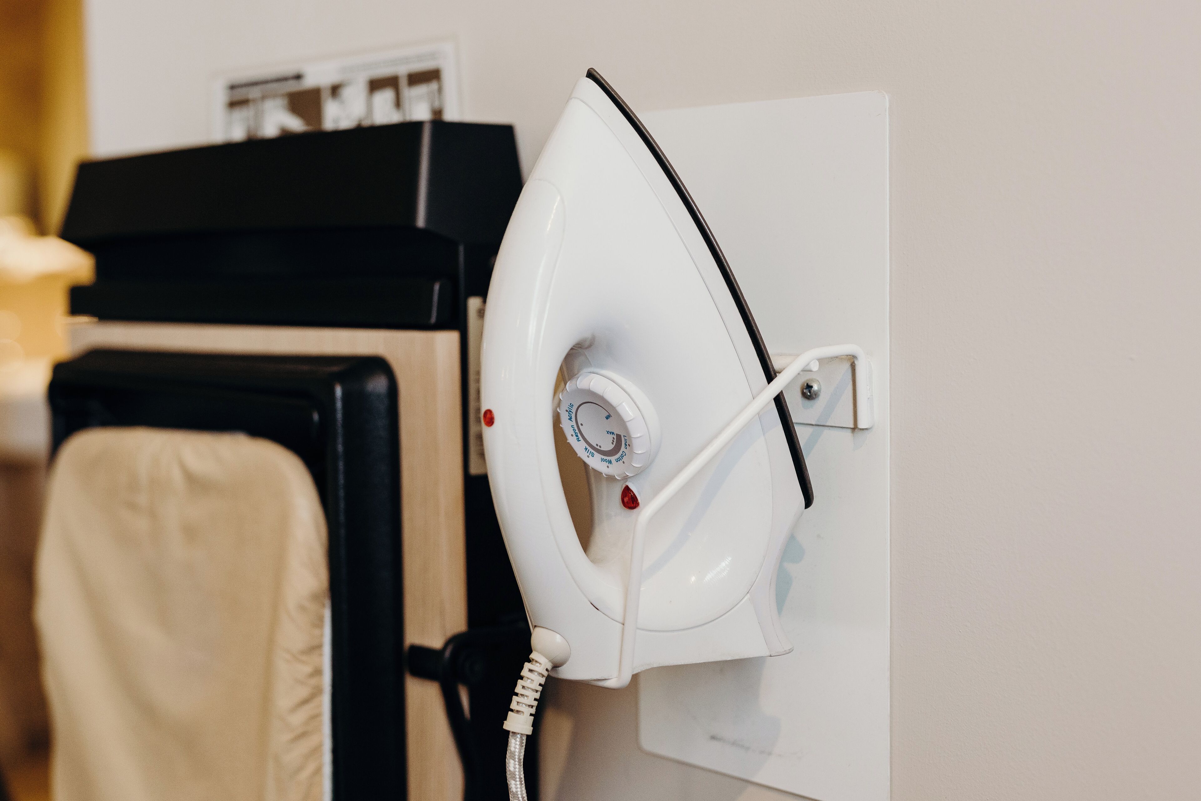 A hair dryer mounted on a wall, a black hair styling tool, and a beige towel.