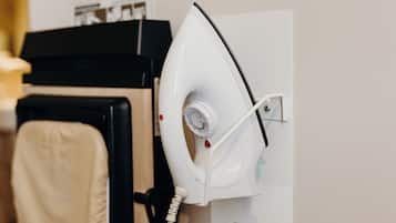 A hair dryer mounted on a wall, a black hair styling tool, and a beige towel.