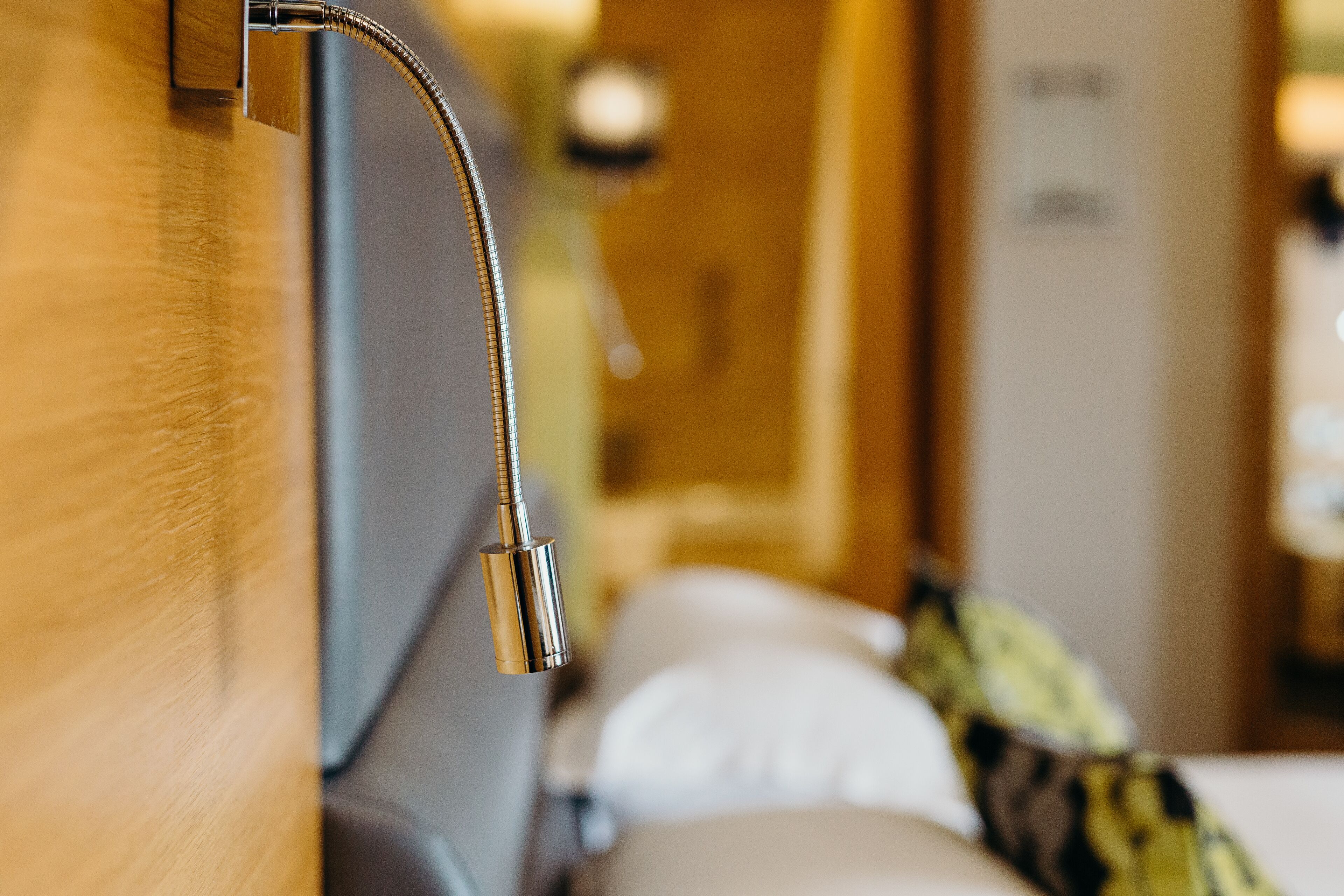 A close-up of a metallic faucet attached to a wooden surface, likely part of a bathroom fixture.