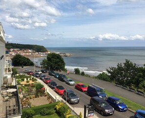 Un aparcamiento con coches, un jardín y vistas al mar y a la ciudad.