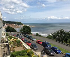 Un aparcamiento con coches, un jardín y vistas al mar y a la ciudad.