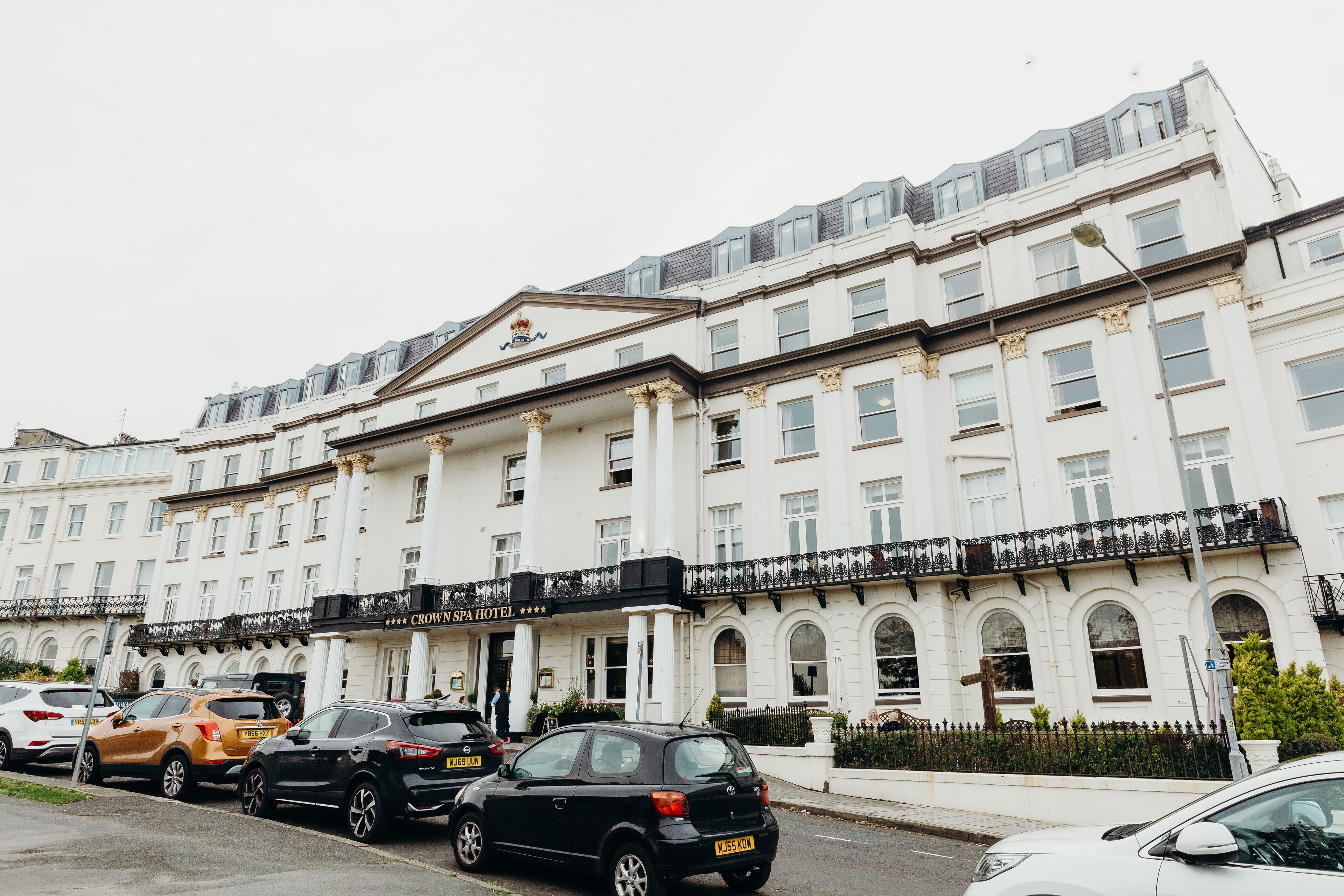 A multi-story hotel with a classic architectural style, featuring a prominent entrance with a black awning and a sign that reads "Crown Spa Hotel."