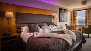 A hotel room with a large bed, a desk, and a chair.