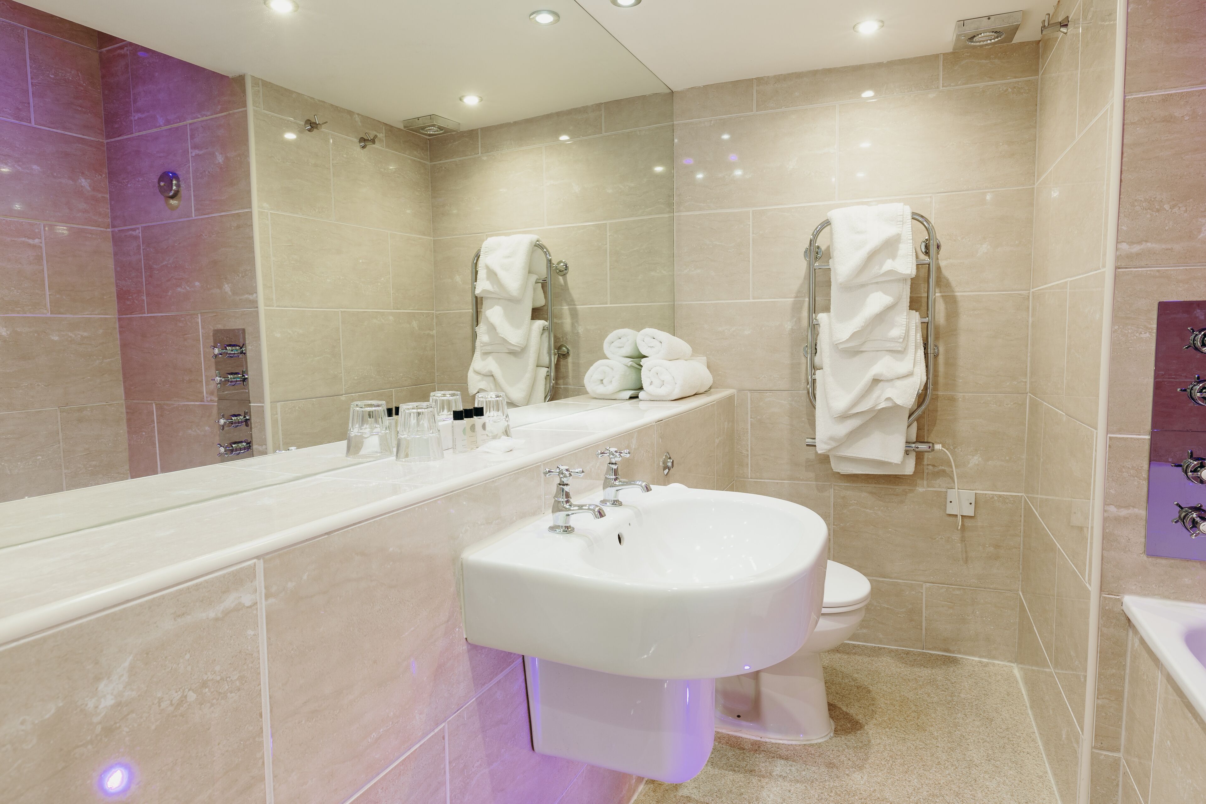 A modern bathroom with a large mirror, a sink, a toilet, and a shower area.