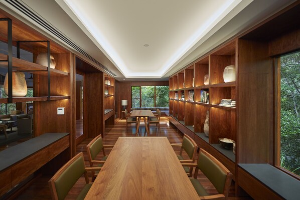 A spacious library with wooden bookshelves, a central table, and comfortable seating.
