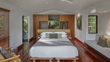 A modern bedroom with a large bed, wooden paneling, and a ceiling fan.