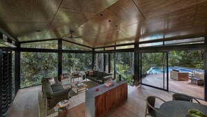 A modern interior with a wooden ceiling, large windows, a pool, and a cozy seating area. - Silky Oaks Lodge, Beckons (Finlayvale)