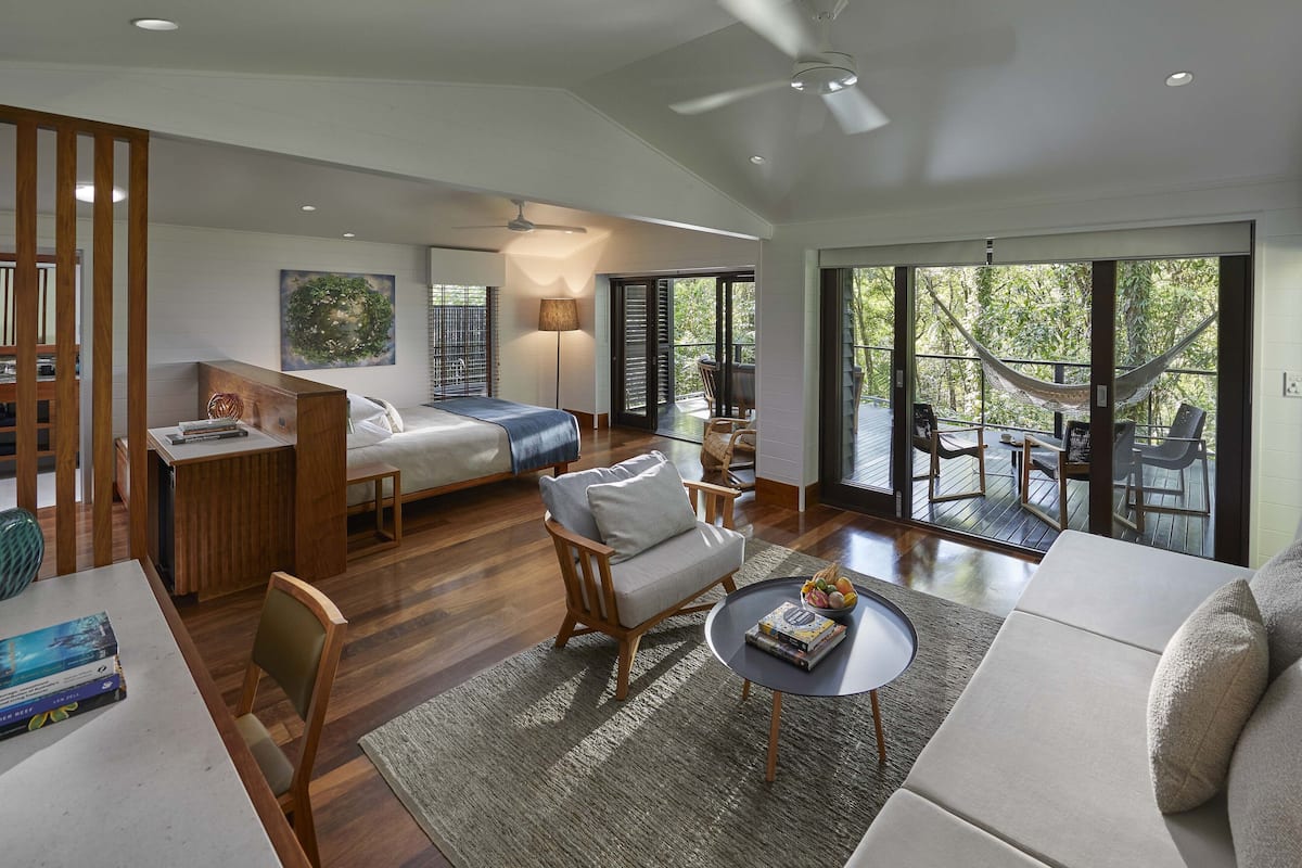 A spacious living area with a large bed, a dining table, and a seating area with a view of the outdoors.