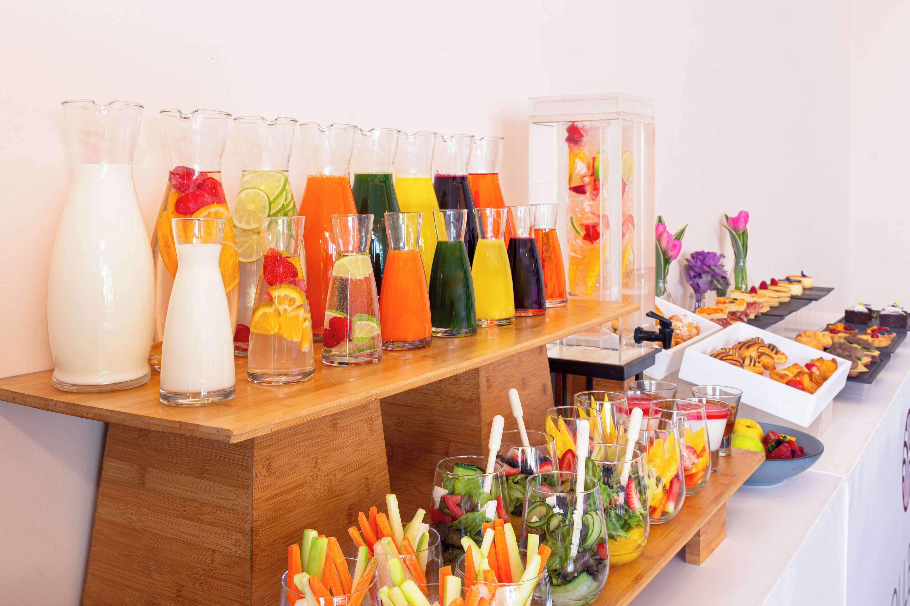 Una mesa de buffet con diversas bebidas y una selección de frutas y verduras.