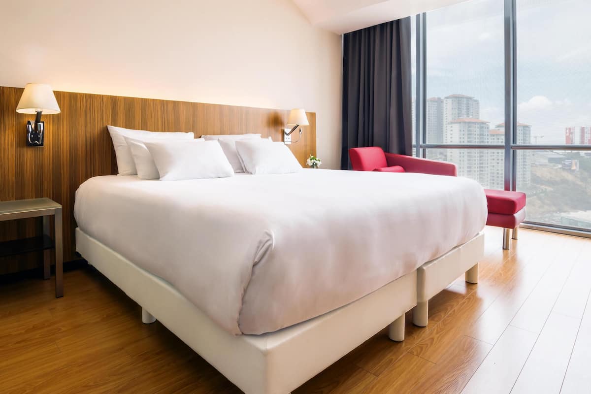 A large bed with white linens, a wooden headboard, and two bedside lamps.