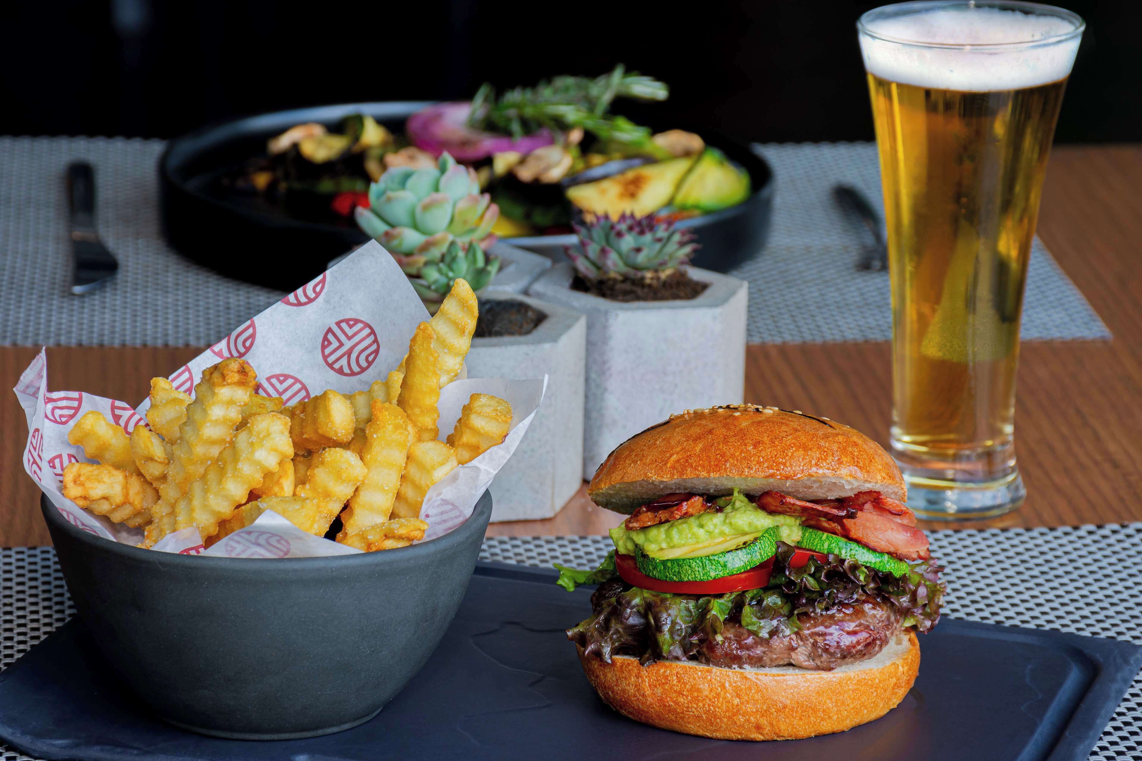 A meal consisting of a burger, fries, and a beer.