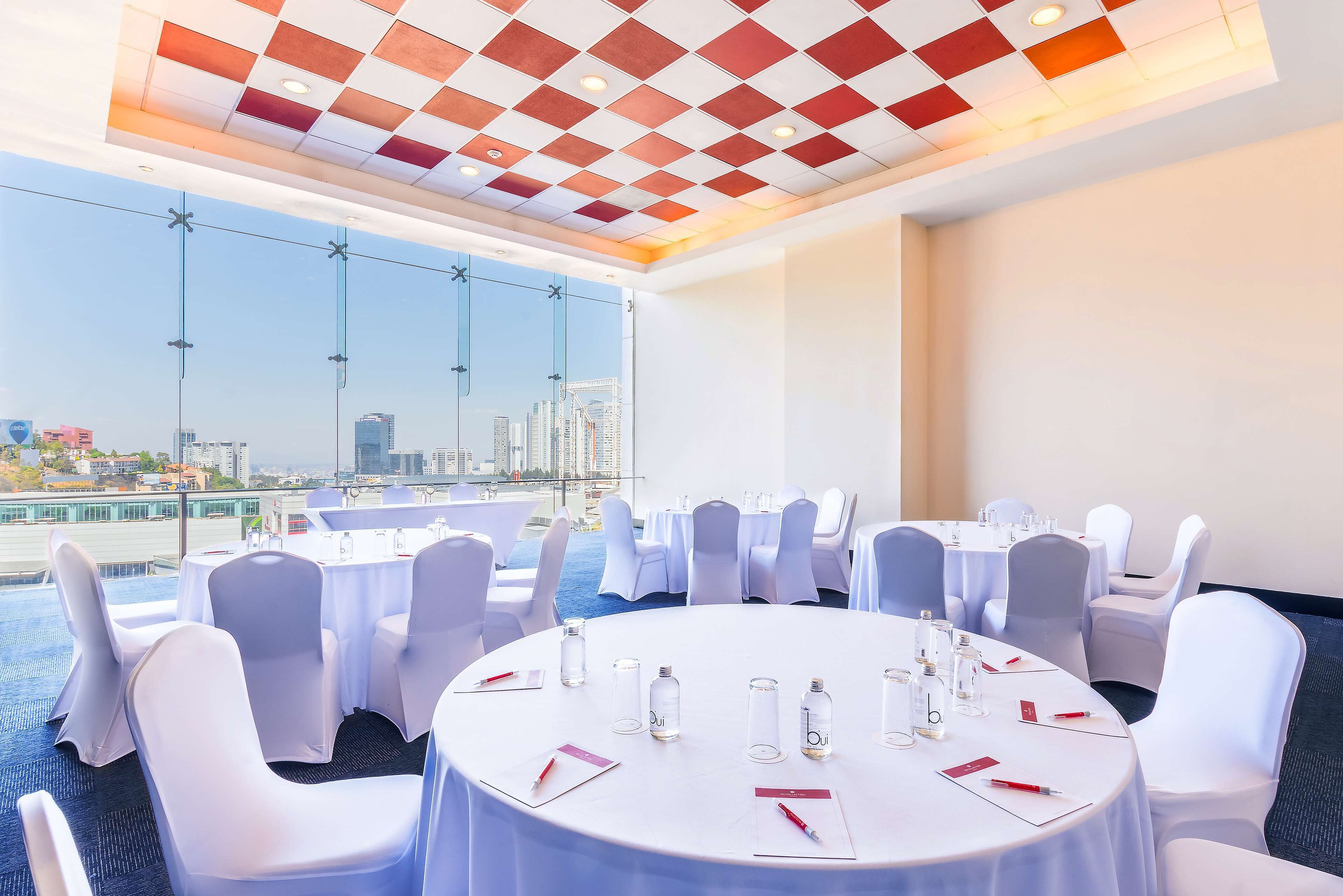 A conference room with round tables, white chairs, and a city view.