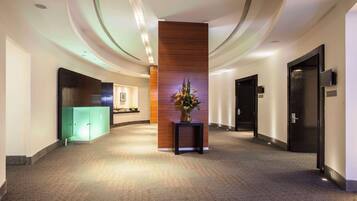 A modern hotel lobby with a curved ceiling, a reception desk, and a decorative plant centerpiece.